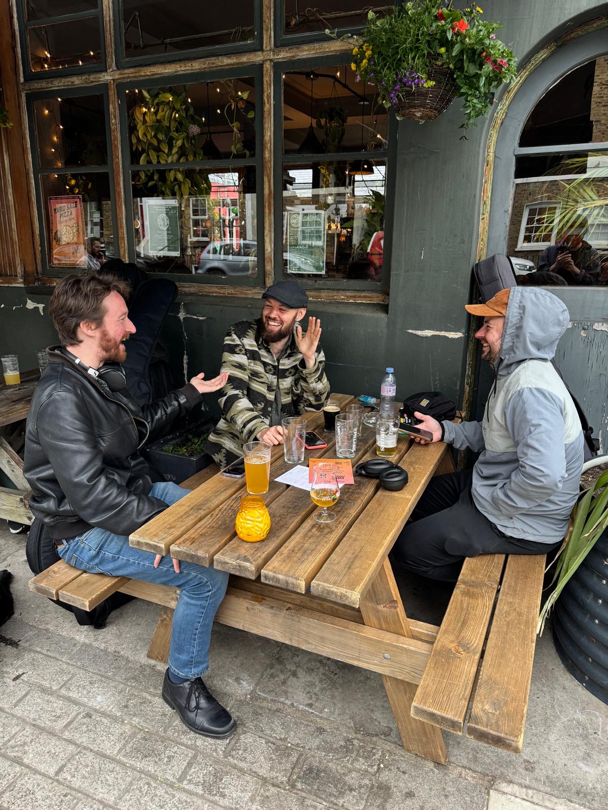 Band members laughing at a pub bench